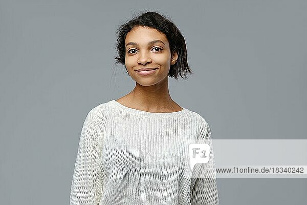 Closeup Porträt der positiven afrikanischen Frau in weißen Strickpullover über grauen Hintergrund