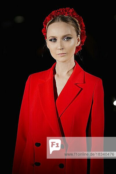 Low-Key-Foto eines schönen Mädchens im roten Blazer mit Blumenkranz im Haar