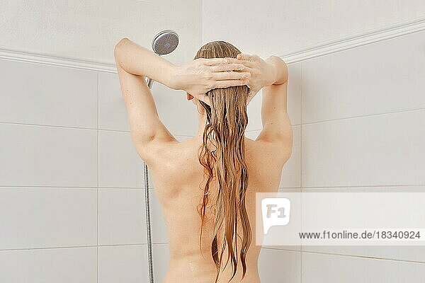 Rückenansicht einer jungen Frau mit gesunder Haut wäscht ihr Haar mit Shampoo im Badezimmer