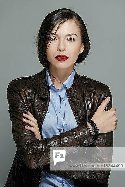 Pretty fashion model in leather jacket with tan makeup and red mat lips