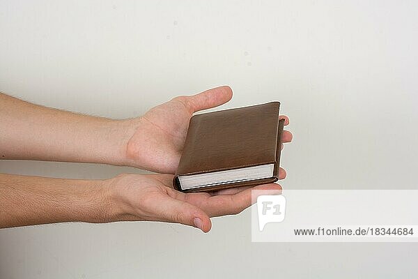 Hand hält braune Farbe Notebook auf einem weißen Hintergrund