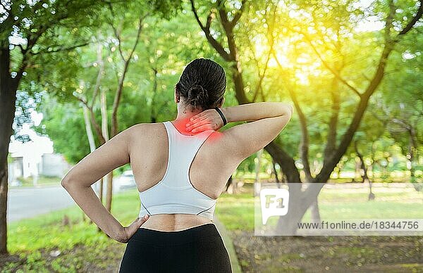 Laufende Frau mit Schultermuskelschmerzen in einem Park. Schulterschmerzen Konzept eines Läufers Athleten. Athleten Mädchen in Schmerzen reiben ihre Schulter im Freien. Rückenansicht einer sportlichen Frau mit Schulterschmerzen