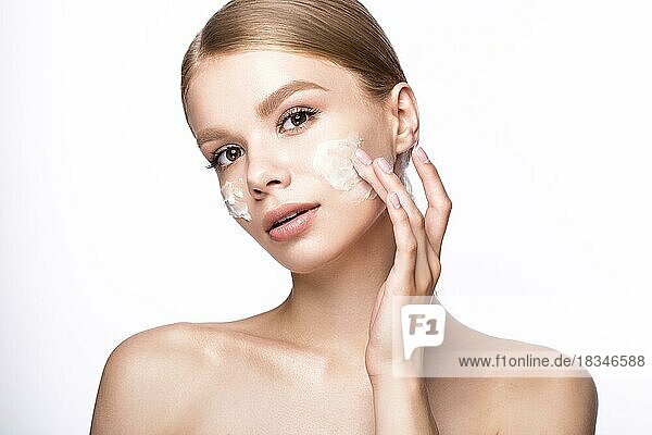 Beautiful young girl with cream on the skin and French manicure. Beauty face. Picture taken in the studio on a white background