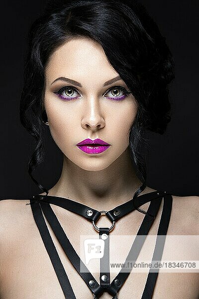 Schönes Mädchen im Gothic-Stil mit Leder-Accessoires und hellem Make-up. Schönheit Gesicht. Bild im Studio auf einem schwarzen Hintergrund genommen