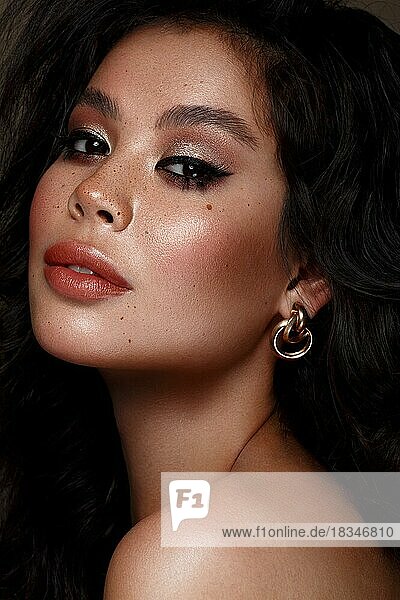 Schöne asiatische brünette Modell mit Volumen Locken  klassische Make-up und sexy Lippen. Die Schönheit des Gesichts. Porträtaufnahme im Studio