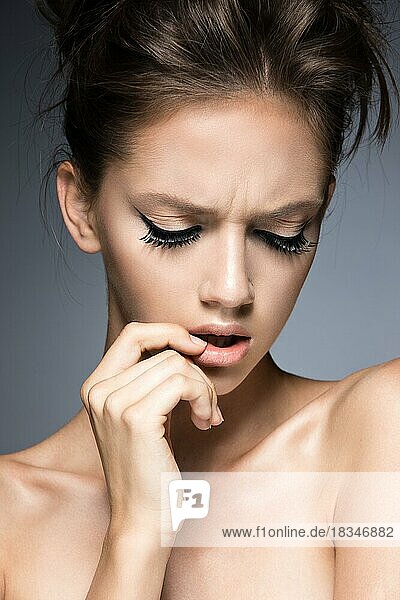Beautiful girl with long eyelashes and perfect skin. Picture taken in the studio on a gray background. Beauty face