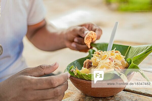 Close-up of person eating vigoron on table. Local person eating a traditional vigorón. The vigoron typical food of Granada  Concept of typical food of Nicaragua