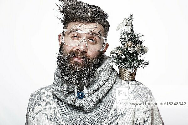 Lustiger bärtiger Mann in einem Neujahrsbild mit Schnee und Dekorationen auf seinem Bart. Fest der Weihnacht. Fotos im Studio aufgenommen