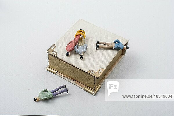 Tiny figurine of men model tied in rope beside a book
