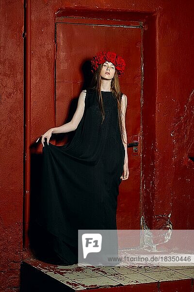 Modemodell in langem Designerkleid und Blumenkranz auf dem Kopf bei Nacht