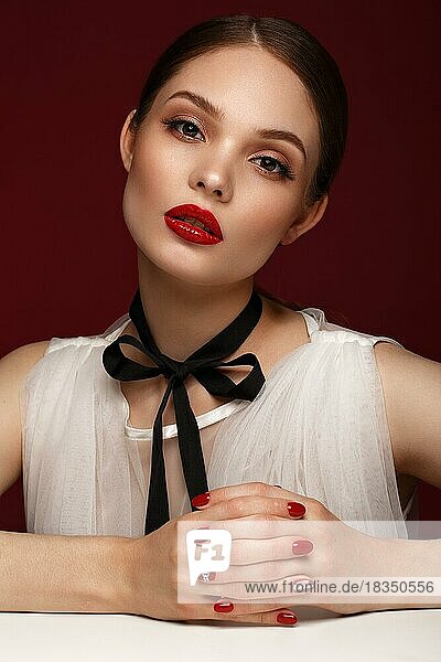 Schönes Mädchen im weißen Kleid mit klassischem Make-up und roter Maniküre. Schönes Gesicht. Foto im Studio aufgenommen