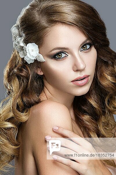 Portrait of a beautiful woman in the image of the bride with flowers in her hair. Picture taken in the studio on a grey background