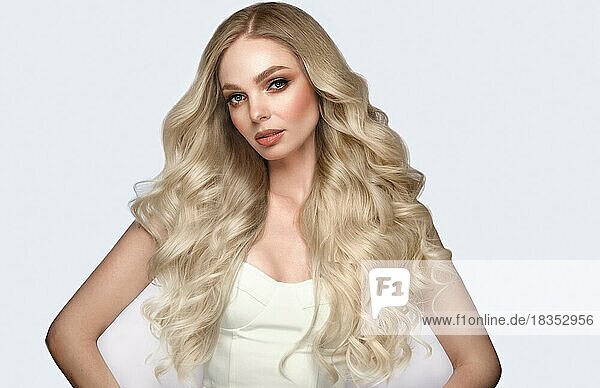 Beautiful blond girl with a perfectly curls hair  and classic make-up. Beauty face and hair. Picture taken in the studio