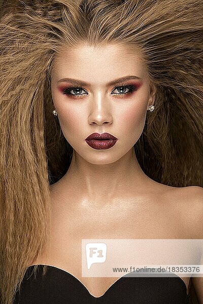 Schöne blonde Modell mit Locken  hellen Make-up und roten Lippen. Die Schönheit des Gesichts. Porträtaufnahme im Studio auf einem braunen Hintergrund