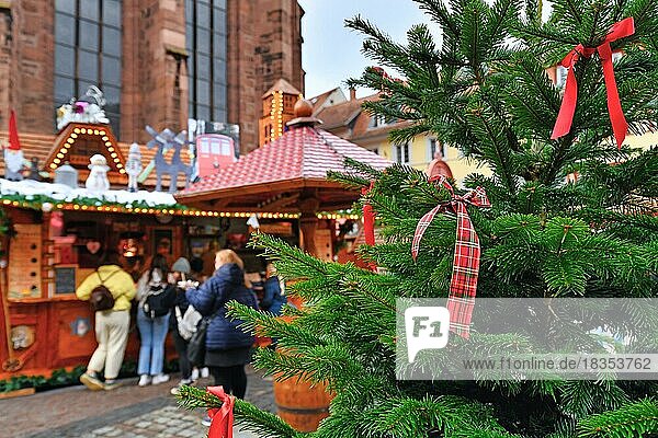 Nahaufnahme eines roten Bandes  das an einen Weihnachtsbaum gebunden ist  mit einem Verkaufsstand und Menschen im unscharfen Hintergrund auf einem traditionellen deutschen Weihnachtsmarkt  Heidelberg  Deutschland  Europa