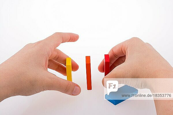 Hand spielt mit farbigen Domino auf weißem Hintergrund
