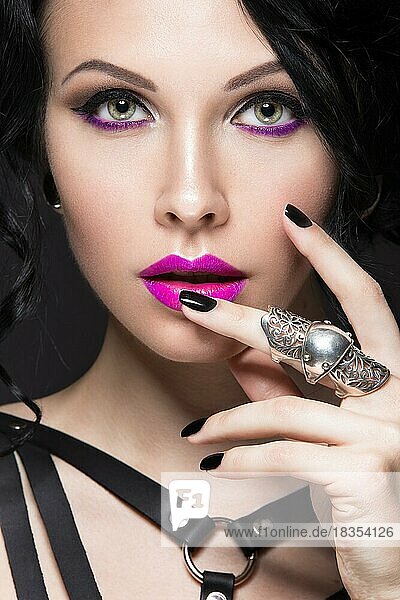Schönes Mädchen im Gothic-Stil mit Leder-Accessoires und hellem Make-up. Schönheit Gesicht. Bild im Studio auf einem schwarzen Hintergrund genommen
