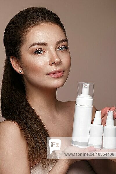 Beautiful young girl with natural nude make-up with cosmetic in hands. Beauty face. Photo taken in studio