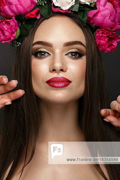 Schönes Mädchen mit hellem Make-up und Blumen auf dem Kopf. Schönes Gesicht. Fotos im Studio geschossen