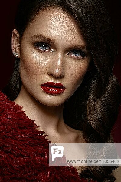 Ein schönes Mädchen mit Abend-Make-up  einer Lockenwelle und roten Lippen. Schönes Gesicht. Foto im Studio aufgenommen