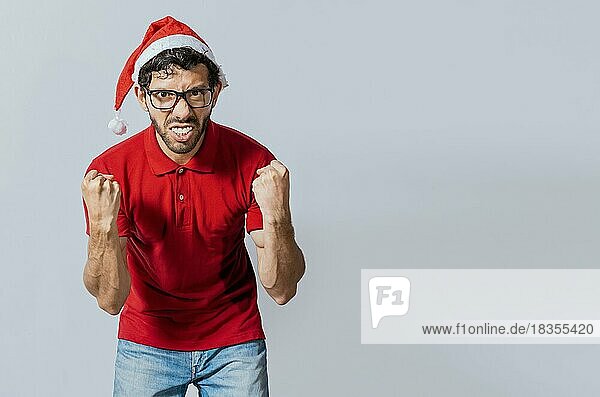Mann mit Bart und Weihnachtsmütze blickt wütend in die Kamera  isoliert. Wütender Weihnachtsmann schaut in die Kamera. Menschen in Weihnachtsmützen wütend und wütend Blick in die Kamera
