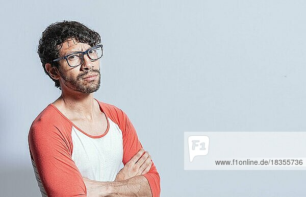 Junger lateinamerikanischer Mann mit Brille und verschränkten Armen schaut im Profil in die Kamera. Nicaragua Mann mit verschränkten Armen Blick in die Kamera isoliert  Porträt eines jungen Mannes mit verschränkten Armen isoliert
