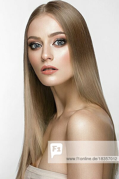 Beautiful blond girl with a perfectly smooth hair  and classic make-up. Beauty face. Picture taken in the studio