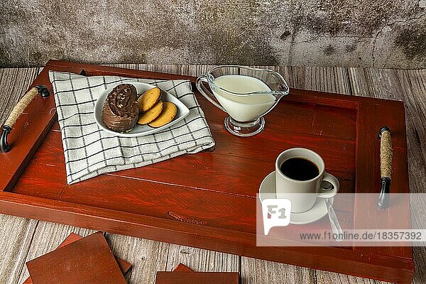 Frühstückstablett aus Holz mit Kaffee  Milch und Gebäck  auf einem Holztisch