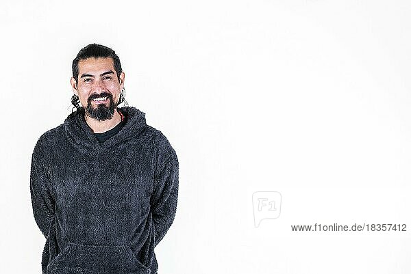 Gutaussehender Latinomann mit Armen hinter sich  lächelnd in die Kamera blickend  vor weißem Hintergrund. Studioaufnahme