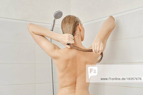 Rückenansicht einer jungen Frau mit gesunder Haut wäscht ihr Haar im Badezimmer