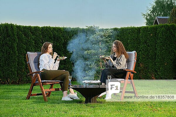 Two women having late evening barbecue picnic outdoors