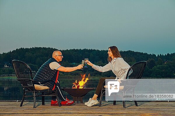 Das Paar feiert den Jahrestag auf dem Steg am Feuer sitzend