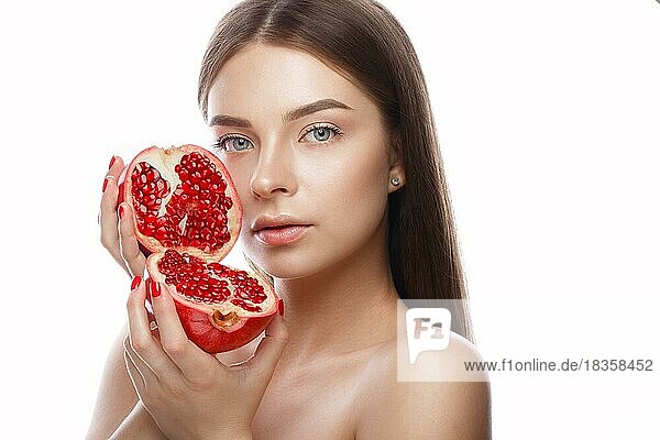 Schönes junges Mädchen mit einem leichten natürlichen Make-up und perfekter Haut mit Granatapfel in der Hand. Schönes Gesicht. Bild im Studio auf einem weißen Hintergrund aufgenommen