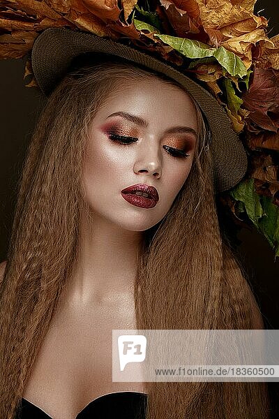 Schöne blonde Modell Herbst Hut mit Locken  hellen Make-up und roten Lippen. Die Schönheit des Gesichts. Porträtaufnahme im Studio auf einem braunen Hintergrund