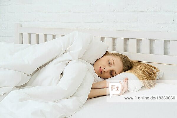 Junge schöne Frau schlafend im Bett mit langen Haaren verstreut auf dem Kopfkissen