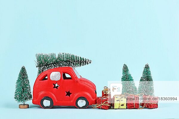 Rotes Auto transportieren Weihnachtsbaum Schneekugeln und Geschenk-Boxen auf blauem Hintergrund mit