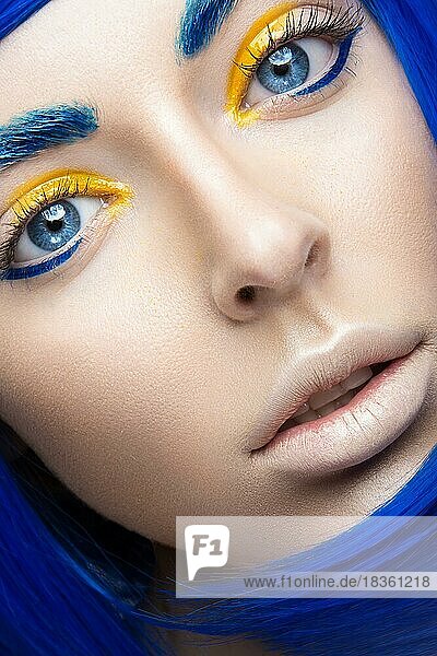 Schönes Mädchen in einer hellblauen Perücke im Stil von Cosplay und kreativem Make-up. Schönheit Gesicht. Kunst Bild. Bild im Studio auf einem gelben Hintergrund genommen