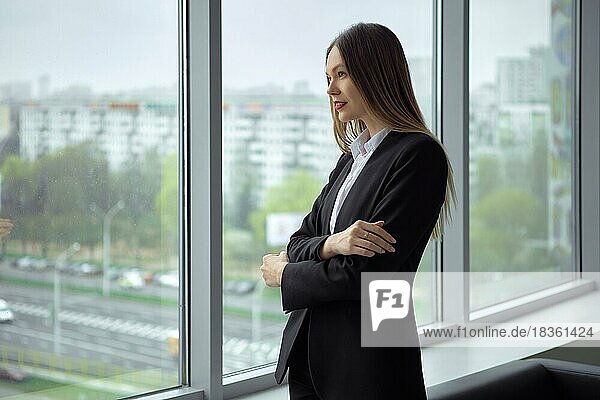 Schöne Geschäftsfrau steht nachdenklich am Fenster