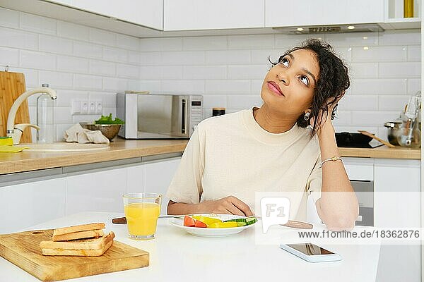 Niedliche afroamerikanische Frau träumt beim Frühstück in der Küche