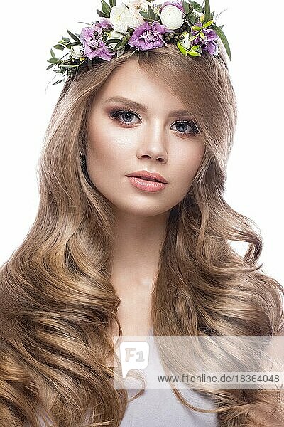 Schönes blondes Mädchen mit sanftem Make-up  Locken und Blumen im Haar. Foto im Studio auf einem weißen Hintergrund aufgenommen