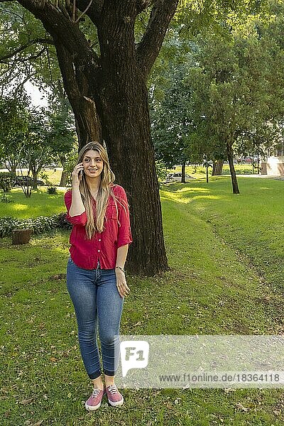 Young blonde woman talking on the phone in the park
