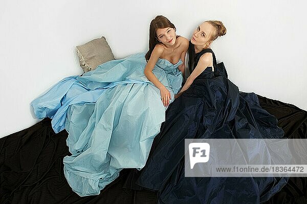 Zwei Modemodelle in flatterndem Kleid auf dem Boden. Fließender Saum