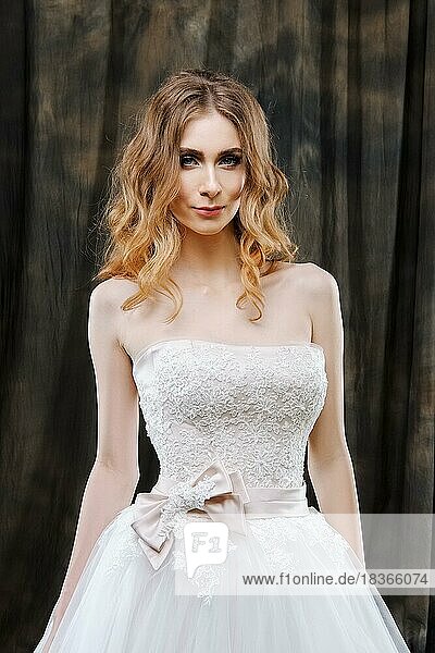 Porträt der hübschen Braut im Hochzeitskleid mit langen lockigen Haaren