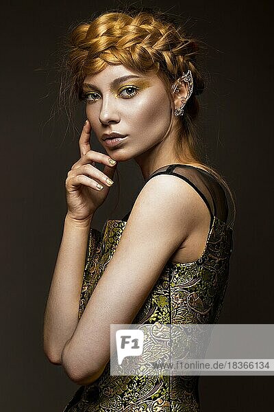 Beautiful girl in a gold dress with creative makeup and braids on her head. The beauty of the face. Photos shot in the studio