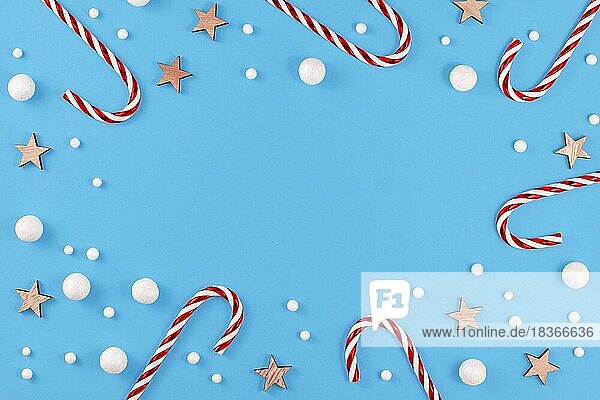 Weihnachten flach legen mit Zuckerstangen  Sterne und Schneebälle auf blauem Hintergrund mit leeren Kopie Raum in der Mitte