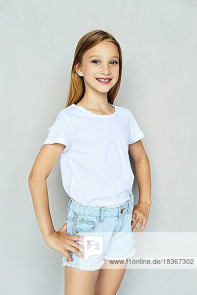 Junges sportliches Mädchen in weißem T-Shirt und Jeansshorts posiert im Studio