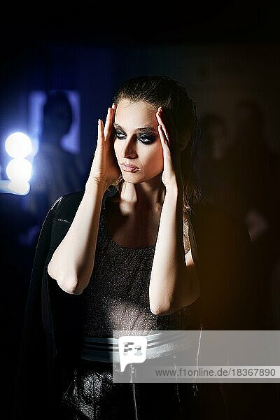 Low key portrait of a girl in dark room. Spotlight lighting fashion model at backstage