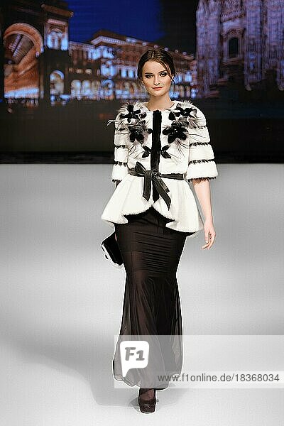 Fashion model walks on runway in fur coat during fashion show