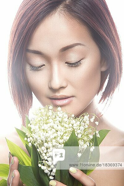 Mode schönes Mädchen orientalischen Typ mit zarten natürlichen Make-up und Blumen. Schönheit Gesicht. Bild im Studio auf einem weißen Hintergrund genommen