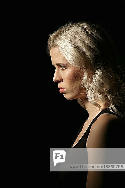 Calm girl with white hair and natural makeup on dark background in profile